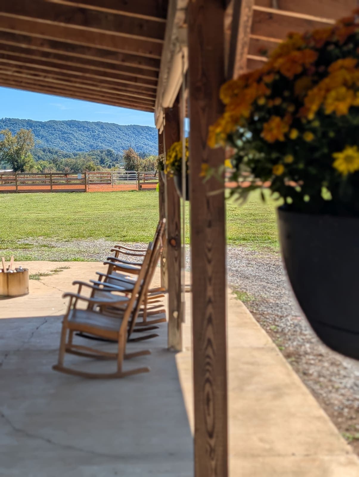 Rocking chairs on the covered porch with hanging mums and mountains beyond